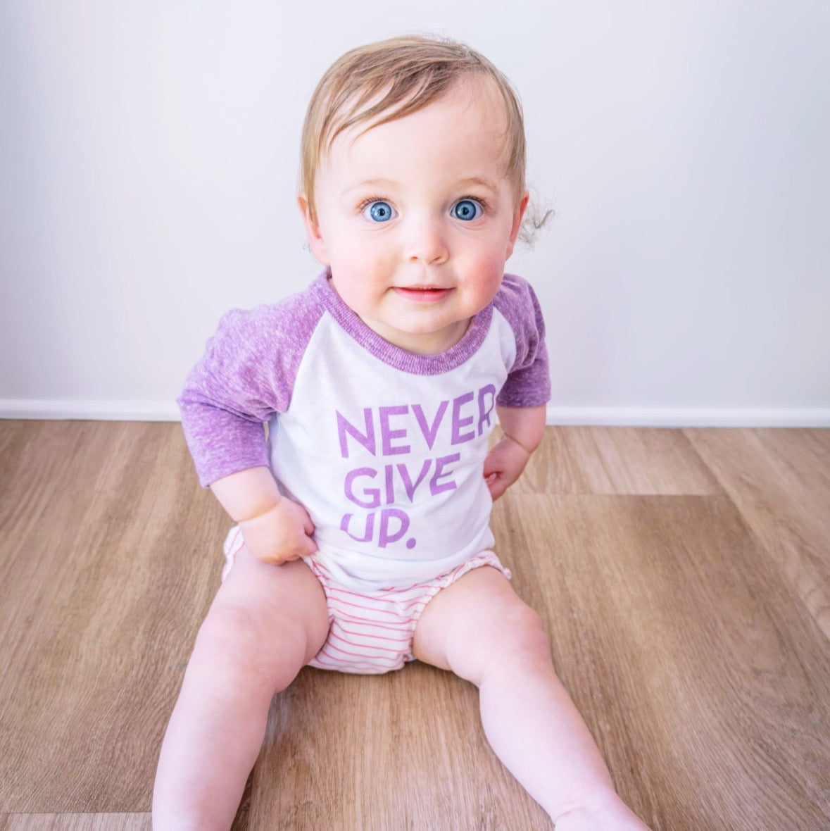 RAGLAN NEVER GIVE UP. BABY TEE