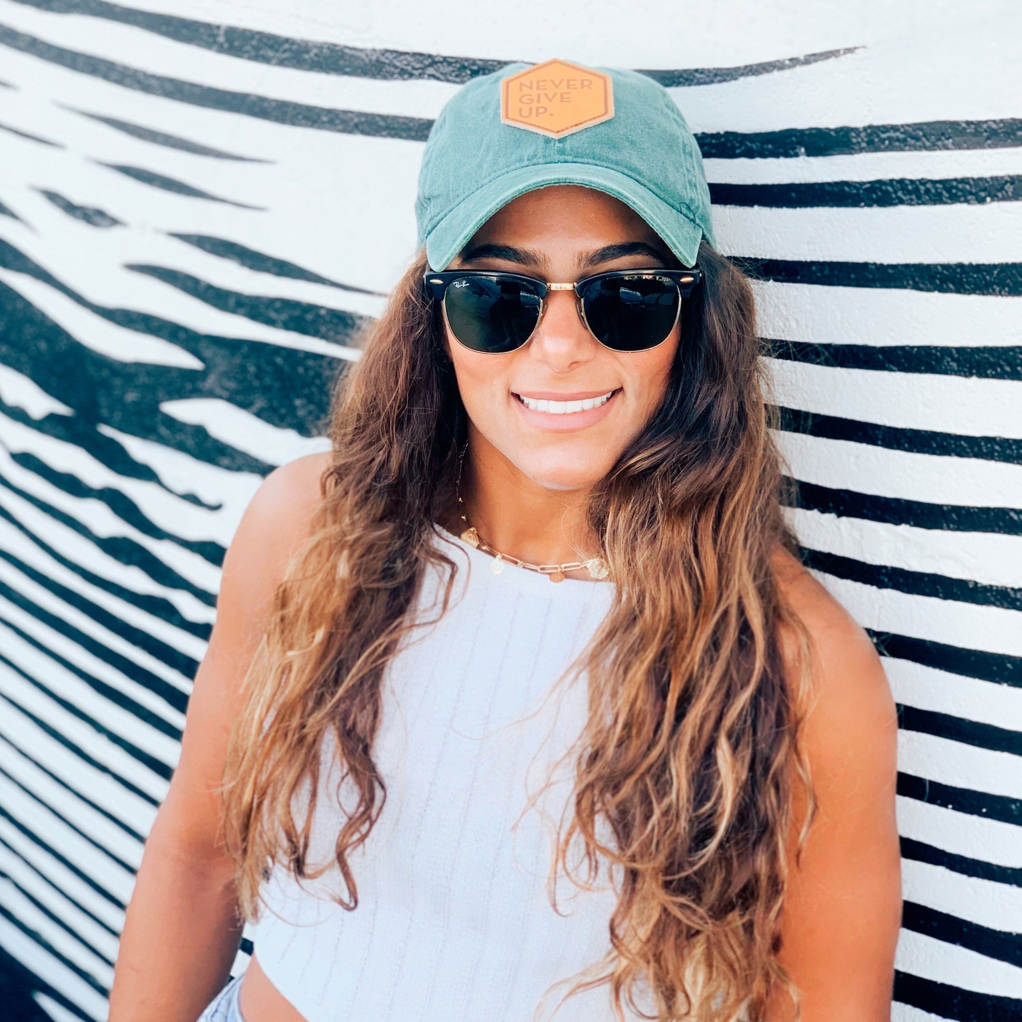 Woman wearing green NEVER GIVE UP. leather patch hat