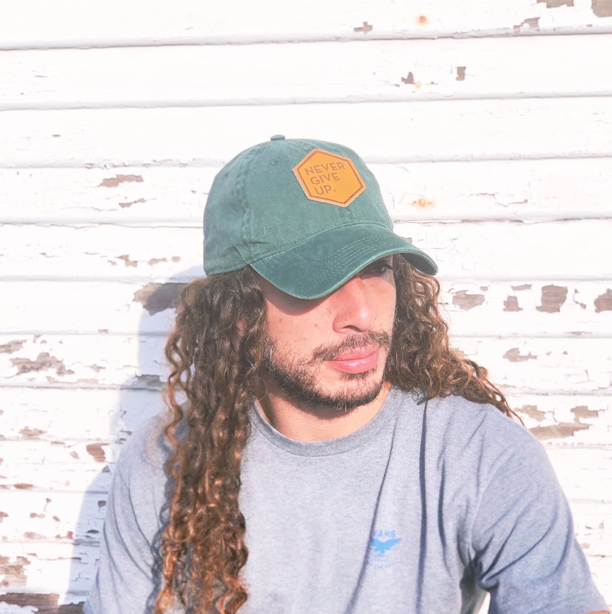 Man wearing green NEVER GIVE UP. leather patch hat