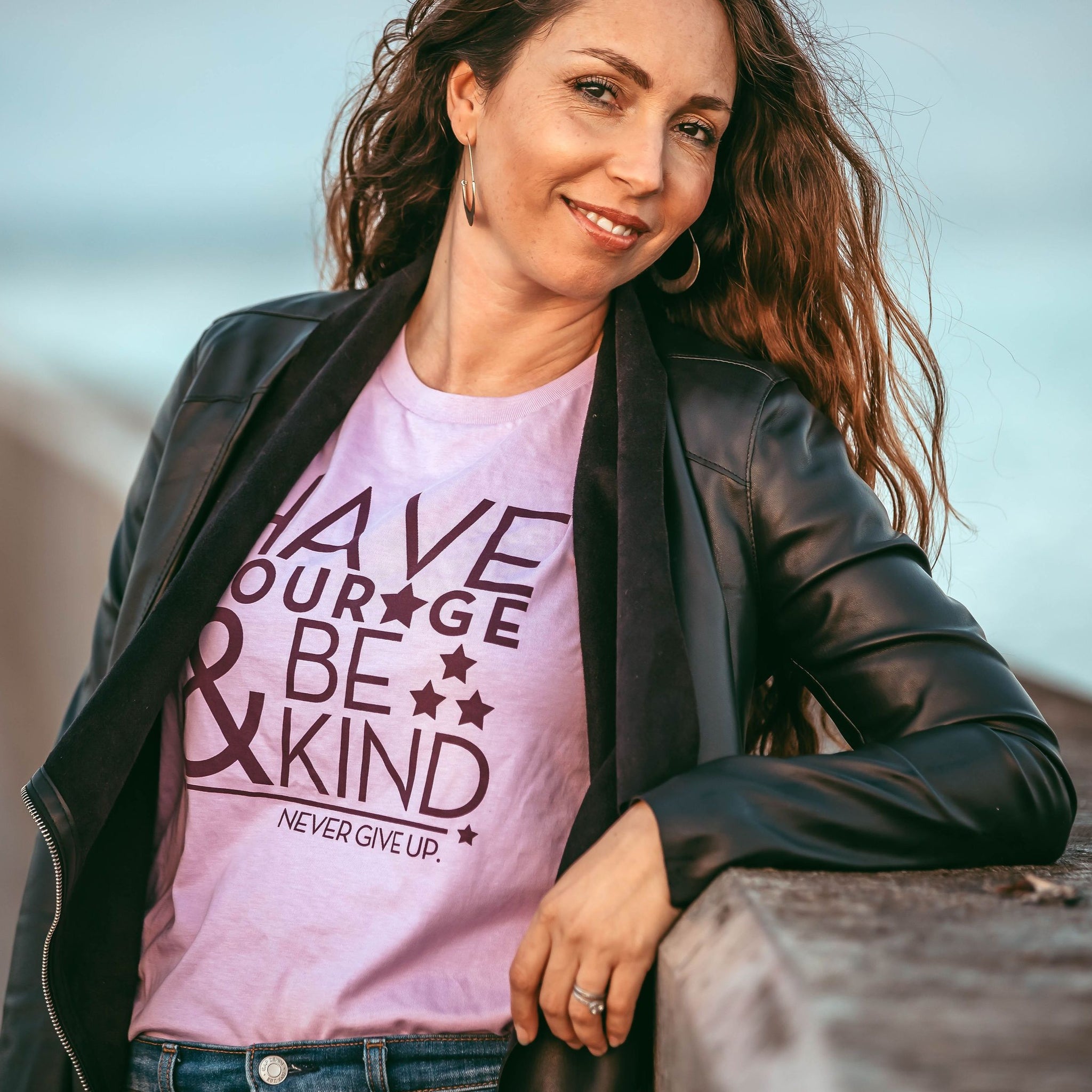 Brunette woman looking at camera wearing Have Courage & Be Kind tee